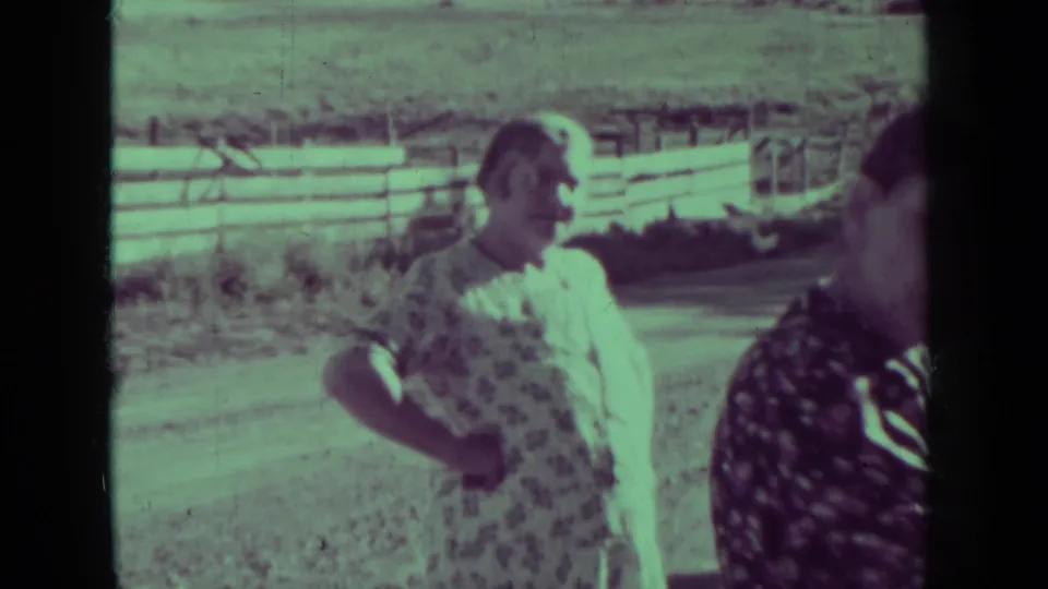 Two women in patterned dresses appear to converse near a wooden fence on a Medford, Oregon neighborhood street in 1937.