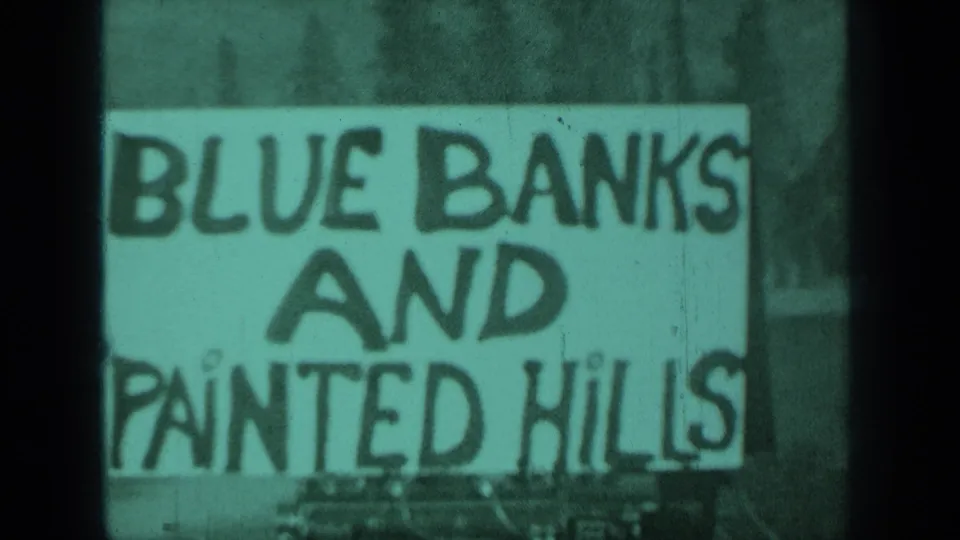 Close-up of the Blue Banks and Painted Hills sign, with soft focus, grain, and green-purple 8mm color shift.