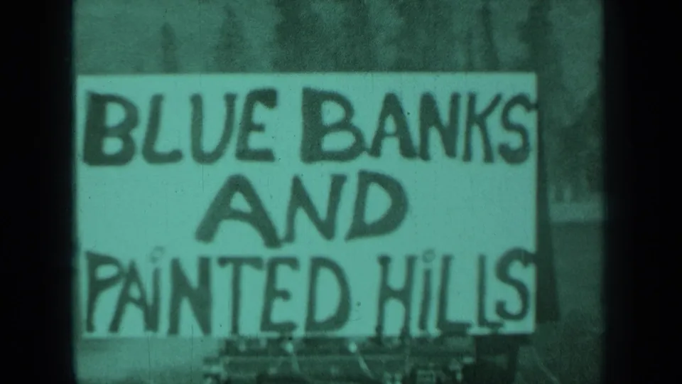 1937 Medford, Oregon 8mm frame showing a hand-painted Blue Banks and Painted Hills sign with soft focus and greenish tint.