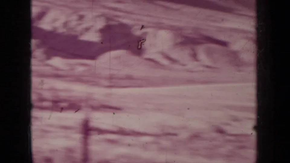 Purple-tinted 8mm view of open ranch land near Medford, Oregon, showing rough ground, slope, and visible scratches.