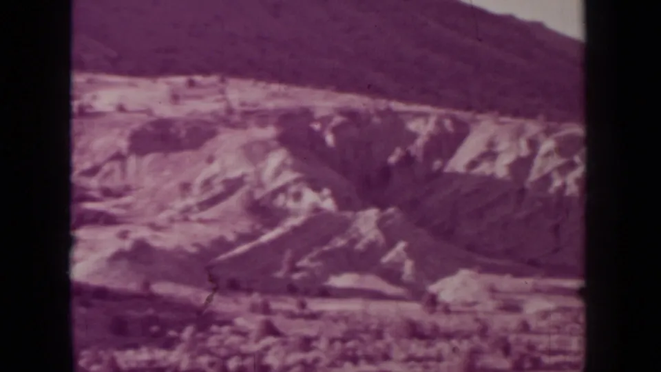 Faded 1937 8mm frame from the Medford, Oregon clip showing a mountain slope and dry open ground.