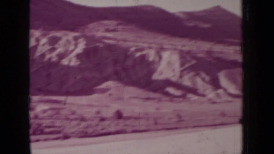 1937 Medford, Oregon frame showing rounded pale hills, darker background ridges, sparse terrain, and strong archival grain with magenta color shift.