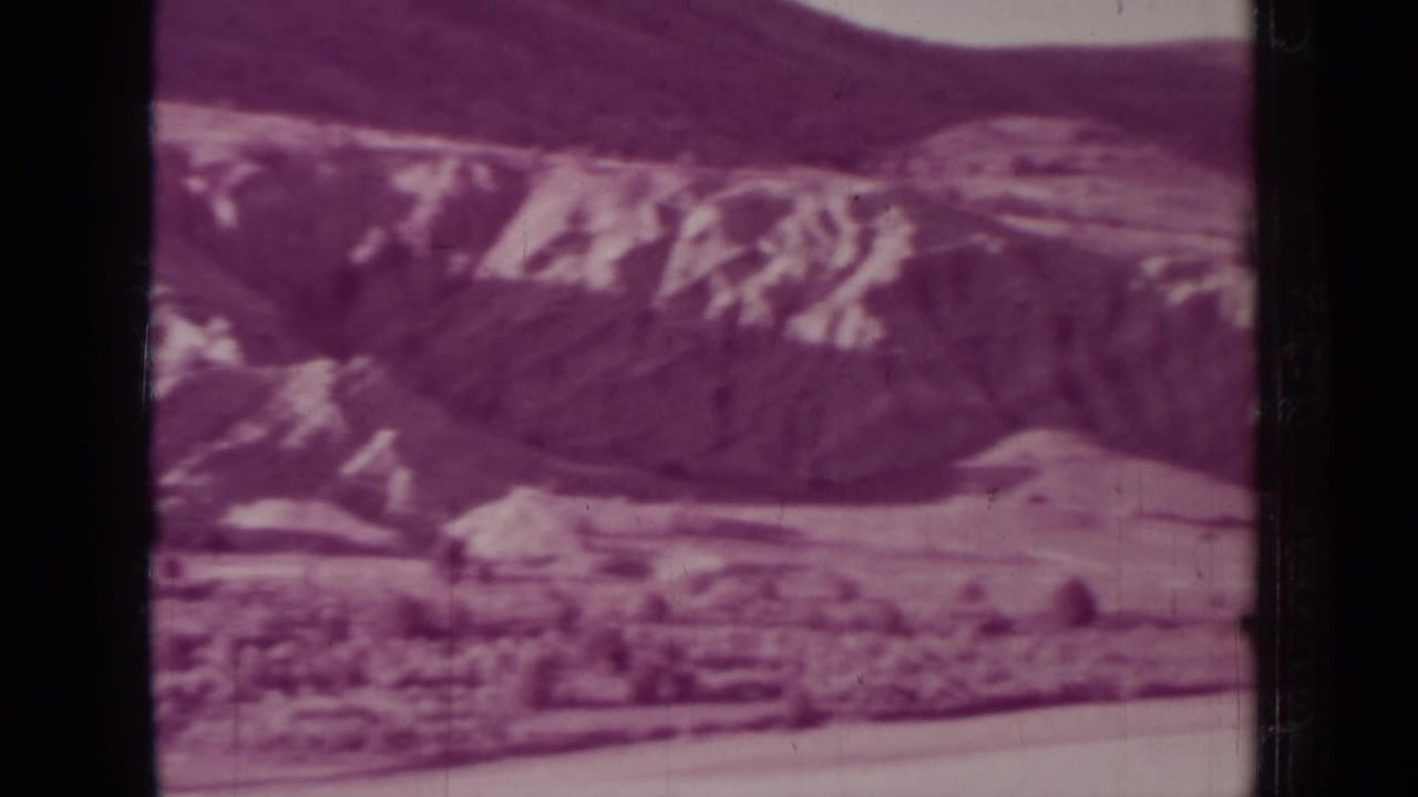 Purple-tinted distant hills and pale ridges seen through 8mm film borders.