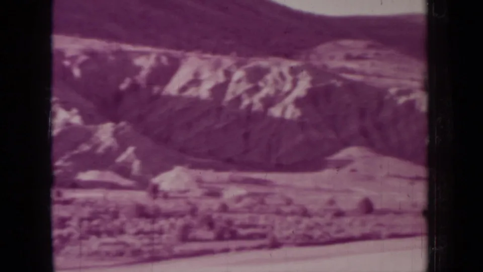 1937 8mm home-movie frame near Medford, Oregon, showing distant rugged hills and pale ridges with dark film gate edges.