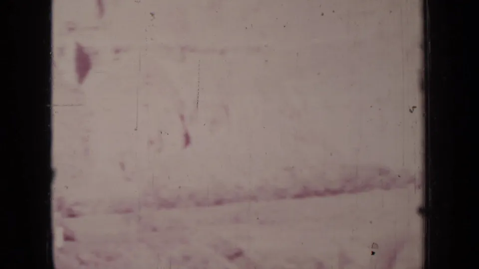 Faded 8mm frame from the Medford, Oregon clip with pale pink landscape texture, soft exposure, scratches, and dark frame edges.