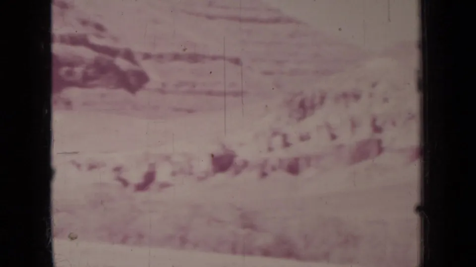 Soft, overexposed 8mm landscape frame from the Medford clip, showing faint hills or ground forms under strong pink color fading.
