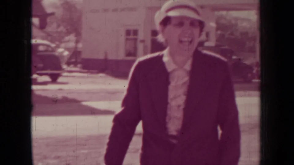 The woman reaches a close distance to the camera on the Medford street, her face visible beneath a brimmed hat.