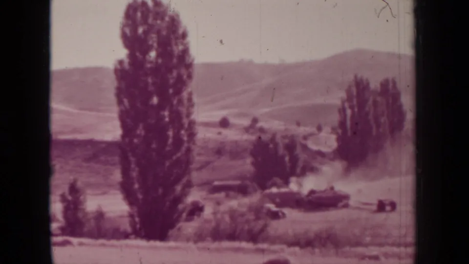 1937 Medford, Oregon home-movie frame showing a tractor area, dust plume, tall trees, field grasses, and rolling hills beyond.