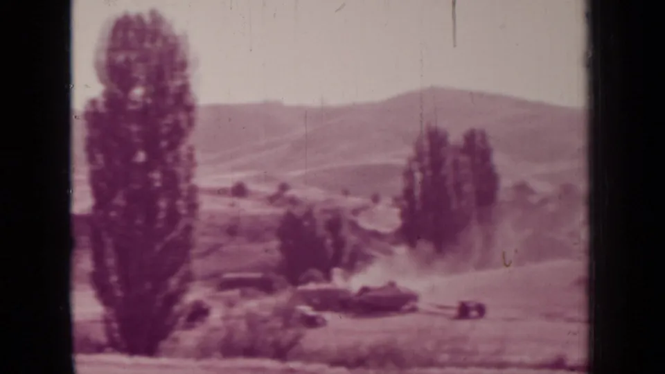 1937 Medford, Oregon frame showing a tractor low in the field, a dust cloud, tall trees, grassy foreground, and hills in the distance.