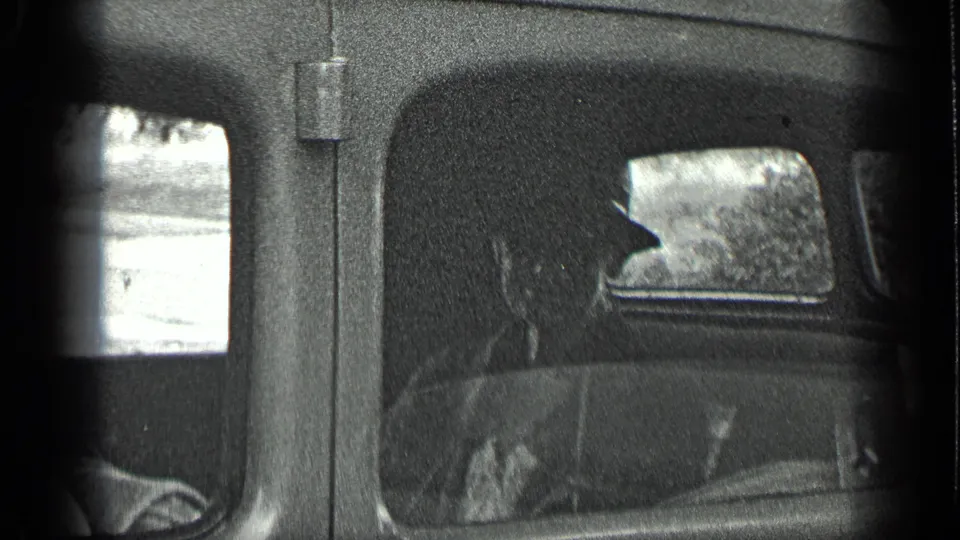 Side-window view in the 1939 Long Lake, Canada home movie shows seated passengers inside a shadowed car interior.