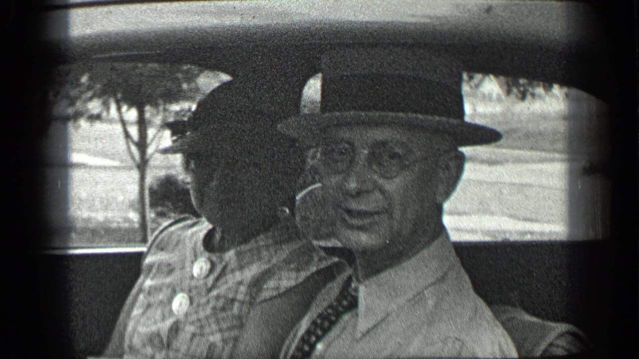 In 1939 home-movie footage from Long Lake, Canada, a man in a fedora smiles from a car seat beside a woman.