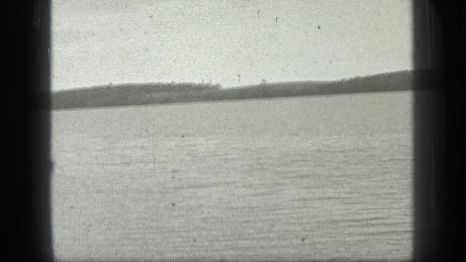 The final frame holds on Long Lake, Canada, showing rippled water and a low wooded shoreline in soft monochrome focus.