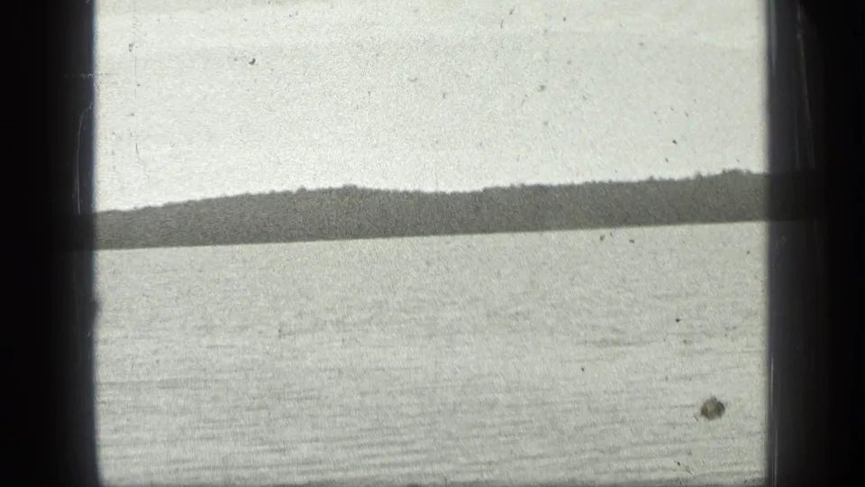 1939 8mm view of Long Lake, Canada, showing a calm water surface, distant shore, pale sky, and the physical edges of the film frame.