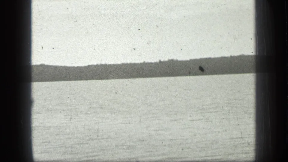 Final 1939 8mm frame of Long Lake, Canada, with textured water, a low far shore, pale sky, and archival film wear visible in the scan.