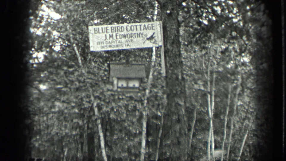 1939 Long Lake frame showing the Blue Bird Cottage sign for J.M. Edworthy among trees, with a small box or birdhouse below.