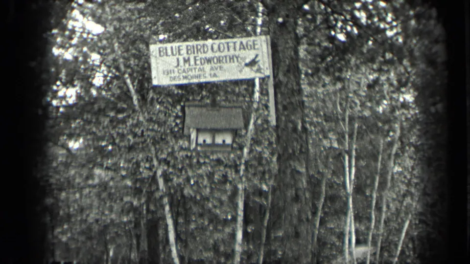1939 Long Lake, Canada home-movie frame showing a Blue Bird Cottage sign and birdhouse in dense woodland.