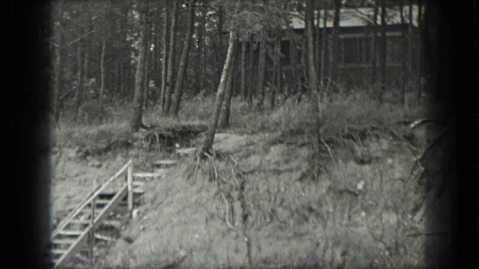 1939 Long Lake, Canada frame showing riverside stairs below a wooded rise, with a rustic building partly visible in the background.