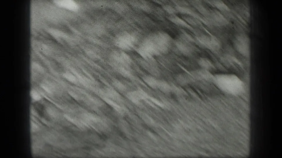 Soft 1939 Long Lake, Canada frame with blurred rocky shoreline texture, shallow water or wet ground, and scattered stones.