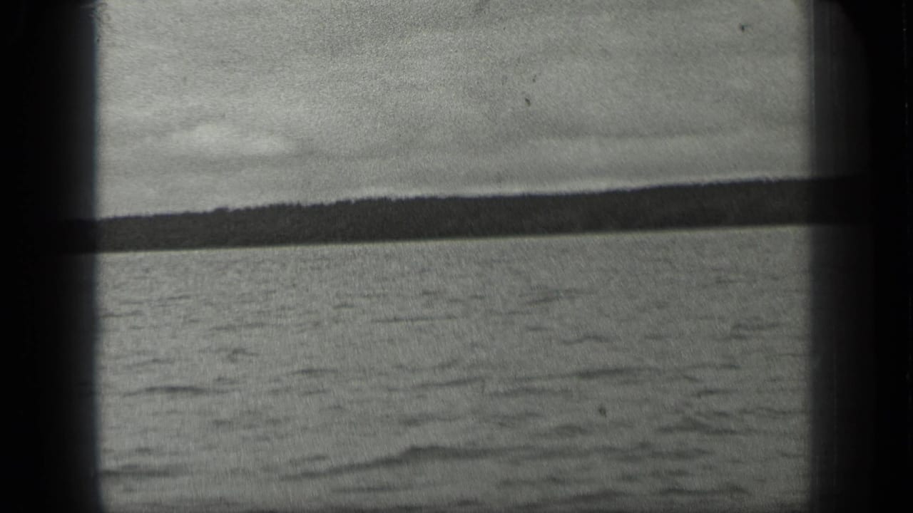 1939 Long Lake, Canada home-movie frame showing rippled water, pale sky, and a distant tree-lined shore through dark 8mm gate edges.