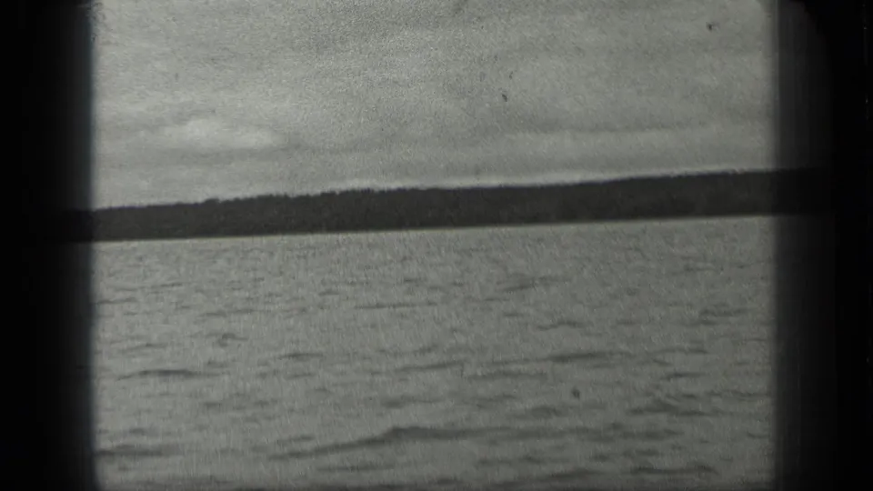 1939 Long Lake, Canada home-movie frame showing rippled water, pale sky, and a distant tree-lined shore through dark 8mm gate edges.