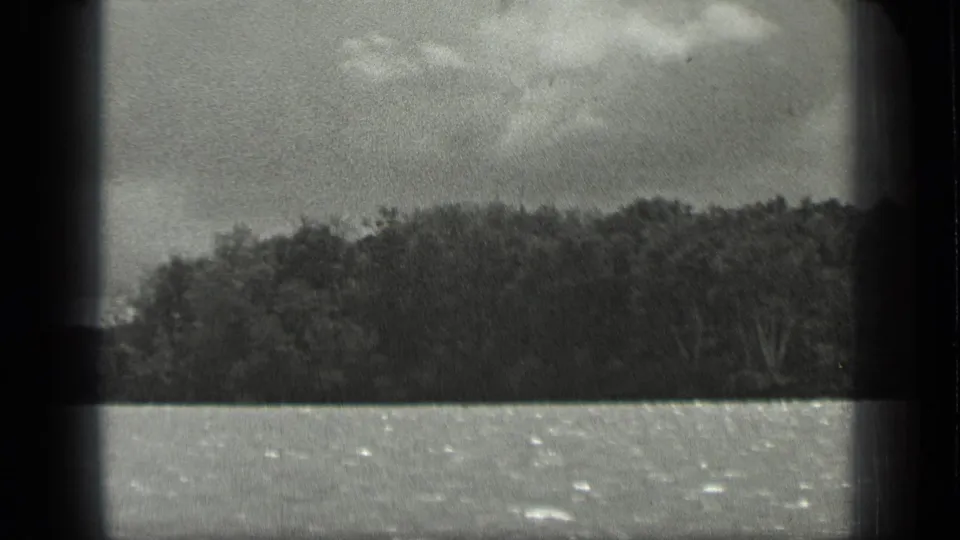 Monochrome 8mm view of Long Lake, Canada, with water in the foreground and trees along the far bank.