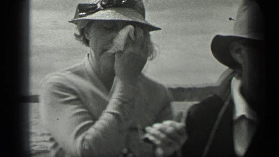 Older woman in a light jacket and brimmed hat sits aboard a boat on Long Lake in 1939, with another hat-wearing passenger beside her.