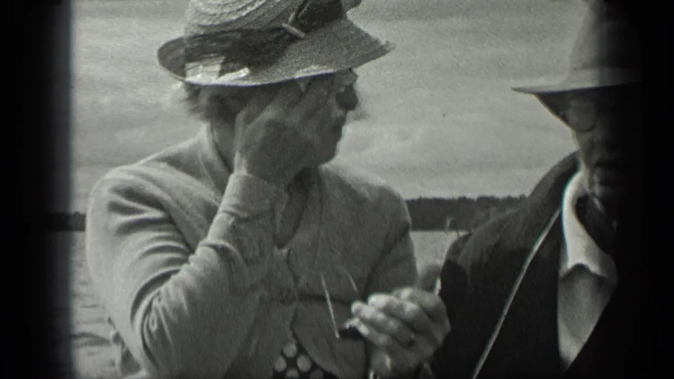 Older woman in a brimmed hat and older man in glasses sit together aboard a boat on Long Lake, Canada, in 1939.