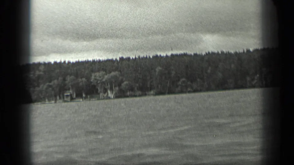 1939 8mm view from a boat on Long Lake, Canada, showing rippled water, dense trees on shore, and a cloudy sky.
