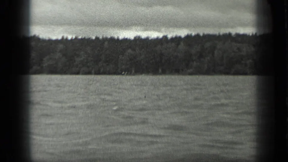 A steady 1939 Long Lake boat view shows open water, a continuous wooded shoreline, and rounded 8mm frame borders.