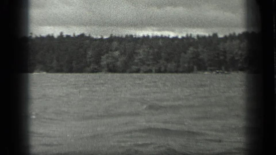 1939 8mm view of Long Lake in Canada, with open water leading to a dark tree-lined shore beneath cloudy sky.