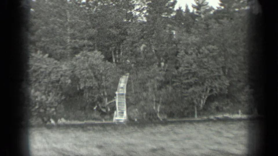 A 1939 Long Lake, Canada frame shows forested shoreline and a narrow wooden stair or dock descending to the water.