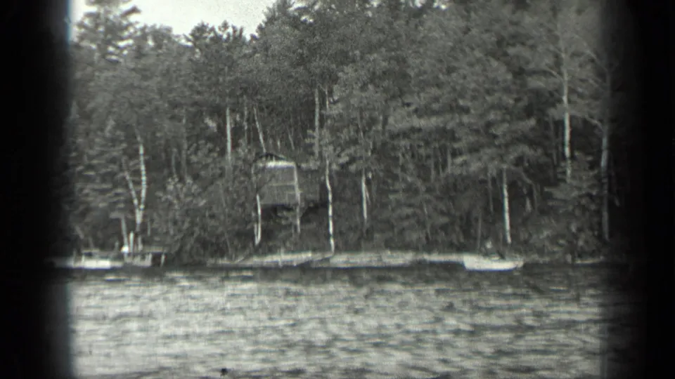 1939 Long Lake, Canada frame with choppy water, dense trees, and a small dock or platform partly visible on the far shore.