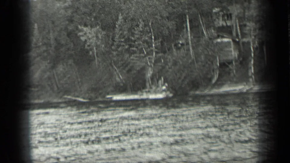 1939 Long Lake, Canada home-movie frame showing a small white boat near a wooden dock on a forested shoreline.