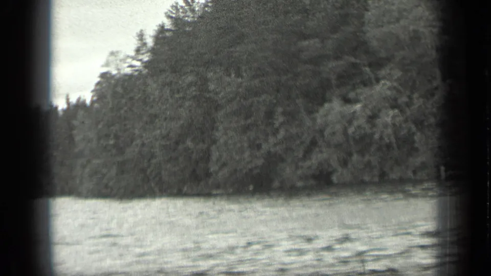 End frame of the 1939 Long Lake, Canada, clip showing rippling water beside a tall, densely wooded shore.