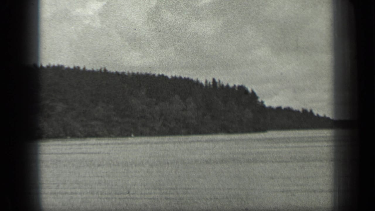1939 Long Lake, Canada view of open water and forested shoreline, with soft black-and-white 8mm grain and frame-edge shadowing.