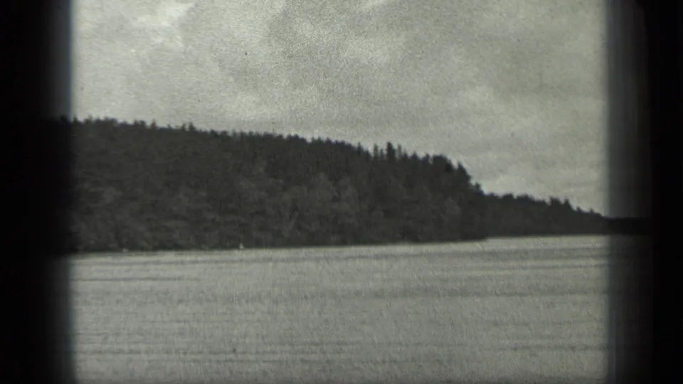 1939 Long Lake, Canada view of open water and forested shoreline, with soft black-and-white 8mm grain and frame-edge shadowing.