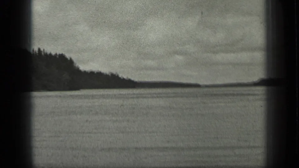 1939 Long Lake, Canada view looking across water between tree-covered shores, with visible 8mm grain and dark frame edges.