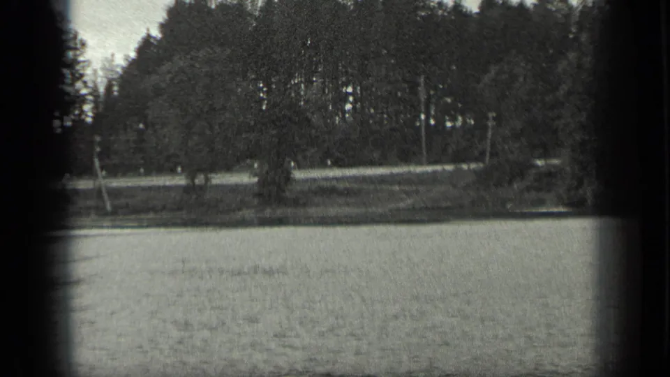 Black-and-white 1939 Long Lake footage showing calm water, trees, shoreline, and soft 8mm frame edges.