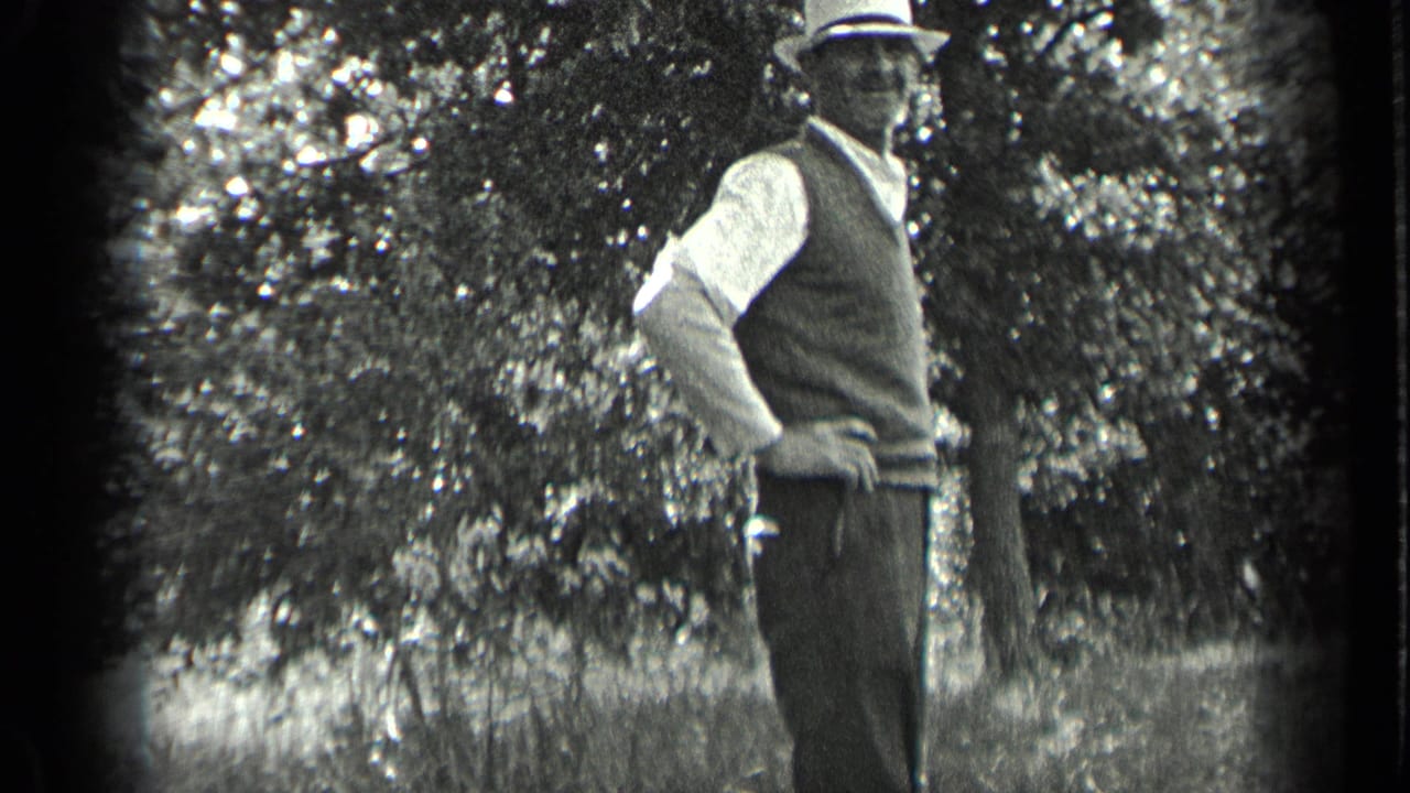 A man in period clothing poses with one hand on his hip outdoors in Long Lake, Canada, surrounded by trees in 1939 footage.