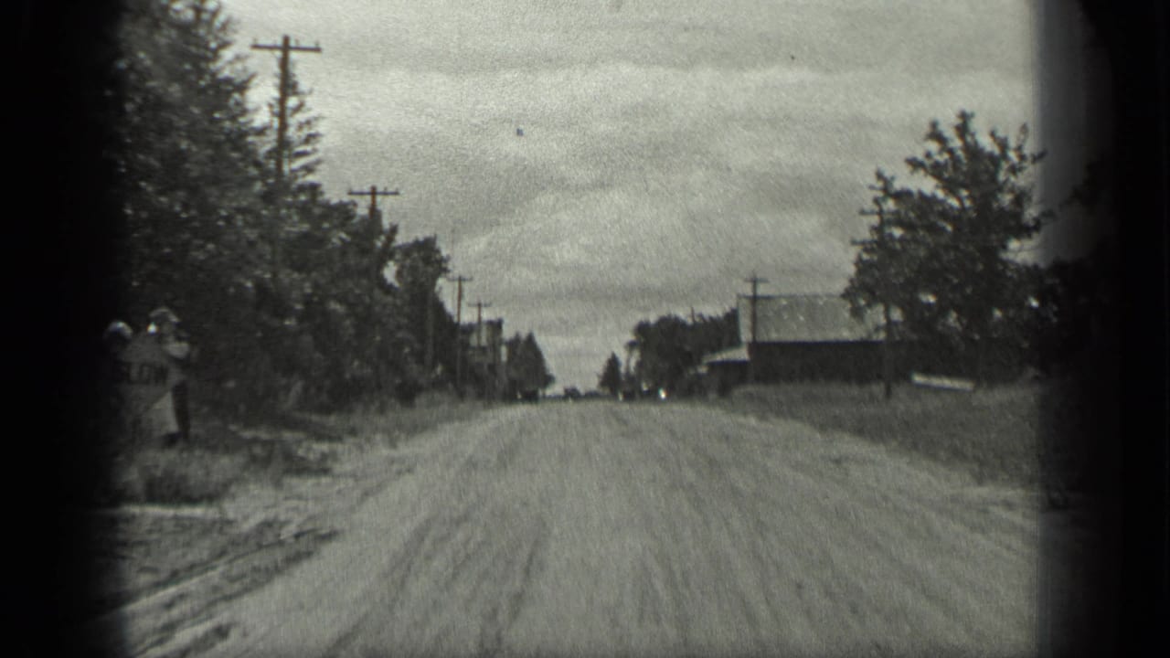 A 1939 rural Long Lake road scene with trees, utility poles, buildings, and a woman beginning to appear along the left roadside.