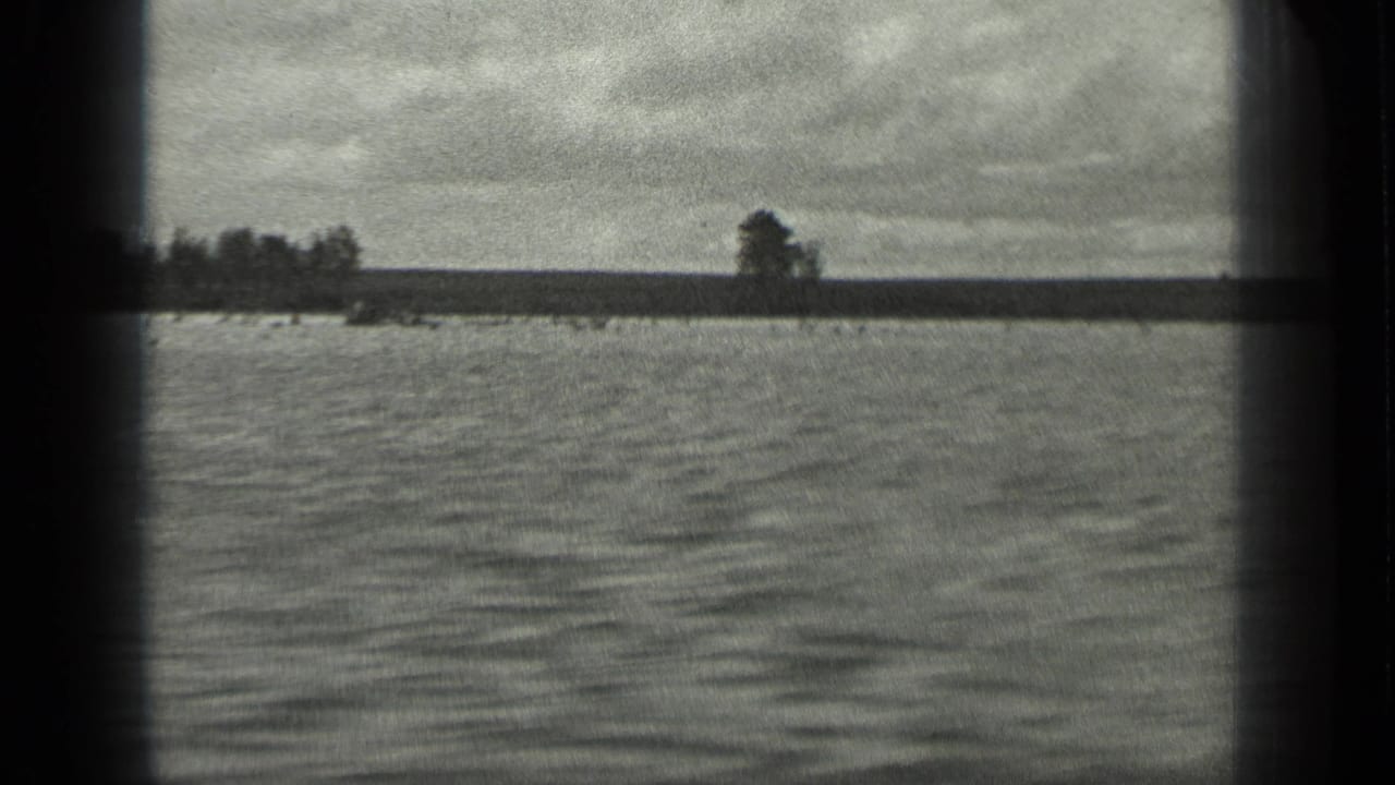 The final Long Lake view holds on rippling water, a flat far shore, isolated trees, cloudy sky, and dark 8mm frame edges.