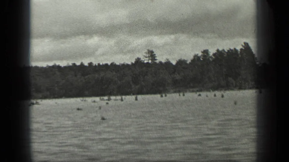 The closing 1939 Long Lake frame shows rippled water, distant trees, cloudy sky, and small indistinct shapes near the lake surface.