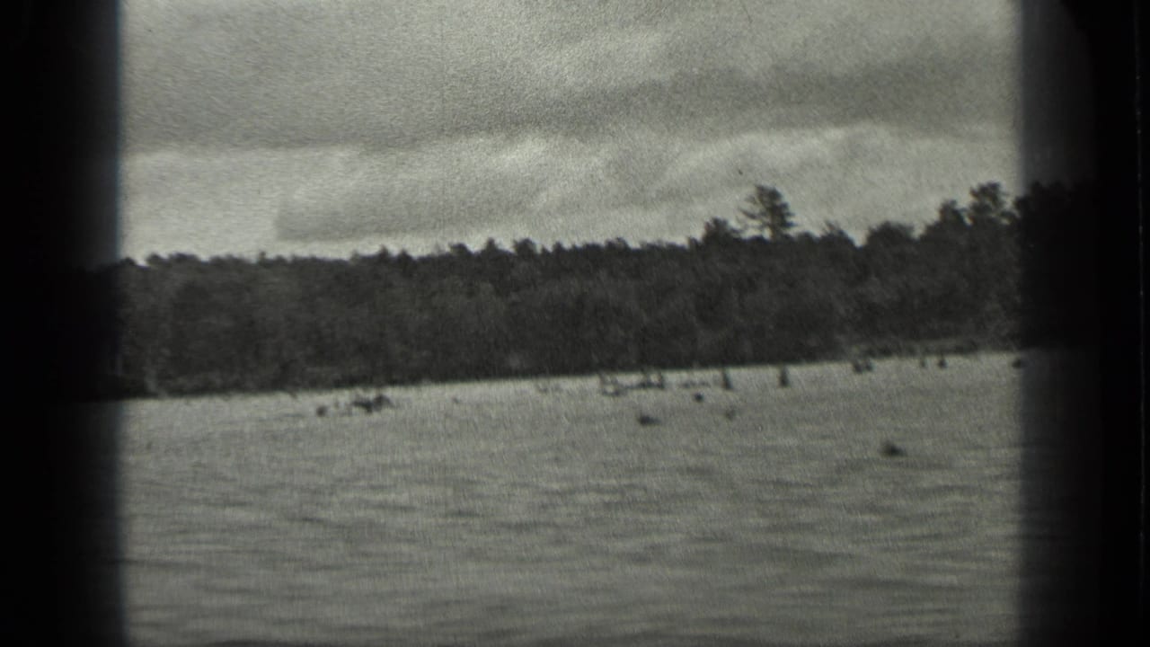 1939 Long Lake, Canada 8mm frame showing open water, a far wooded shoreline, overcast sky, and visible film gate borders.