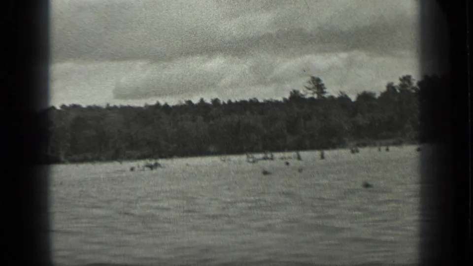 1939 Long Lake, Canada 8mm frame showing open water, a far wooded shoreline, overcast sky, and visible film gate borders.