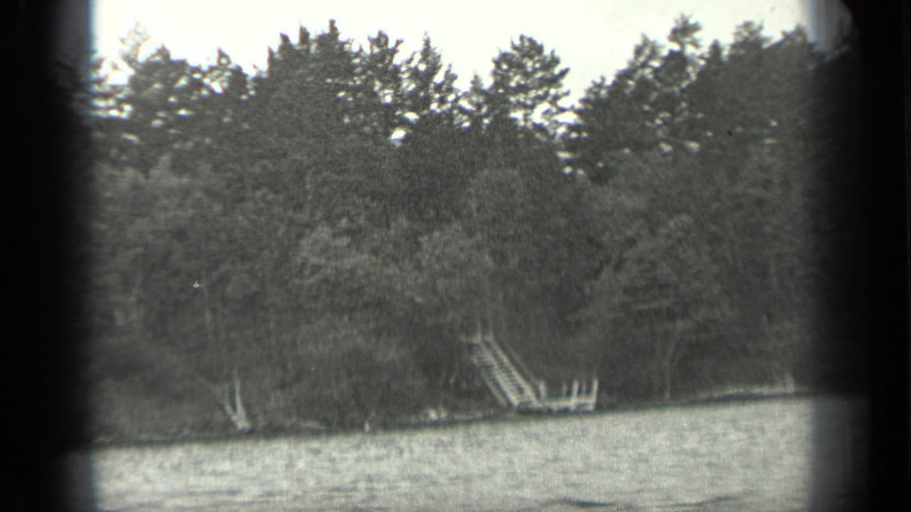 1939 Long Lake, Canada 8mm frame showing the wooded shore, rippled water, and a small wooden dock or ladder set into the bank.