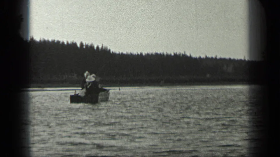 Two people appear seated in a small fishing boat on Long Lake, Canada, in 1939-era black-and-white 8mm footage.