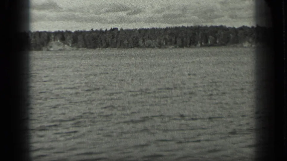 Long Lake water and a low wooded shoreline appear in a soft, grainy 1939 home-movie frame.