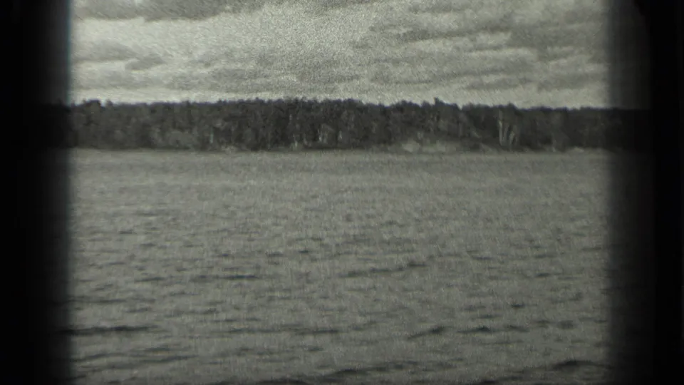 1939 Long Lake, Canada home-movie frame showing rippled water, far treeline, cloudy sky, and dark 8mm frame edges.