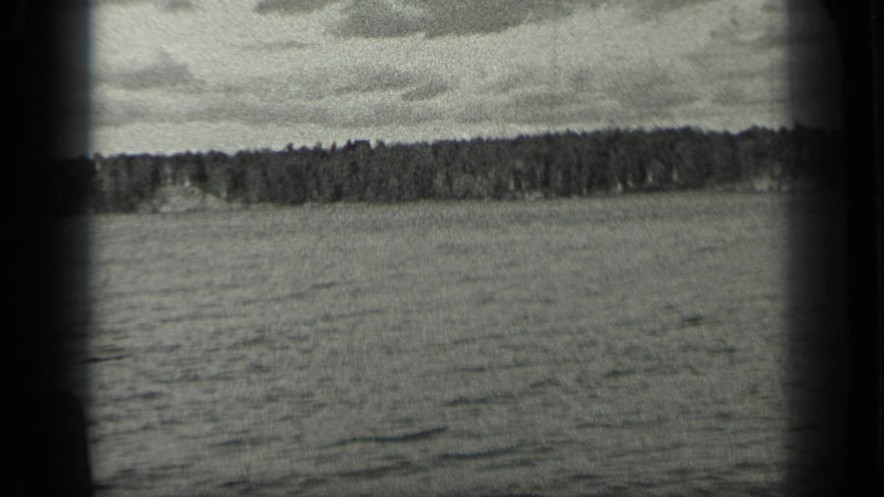 Open lake and low forested shore framed by dark film edges.