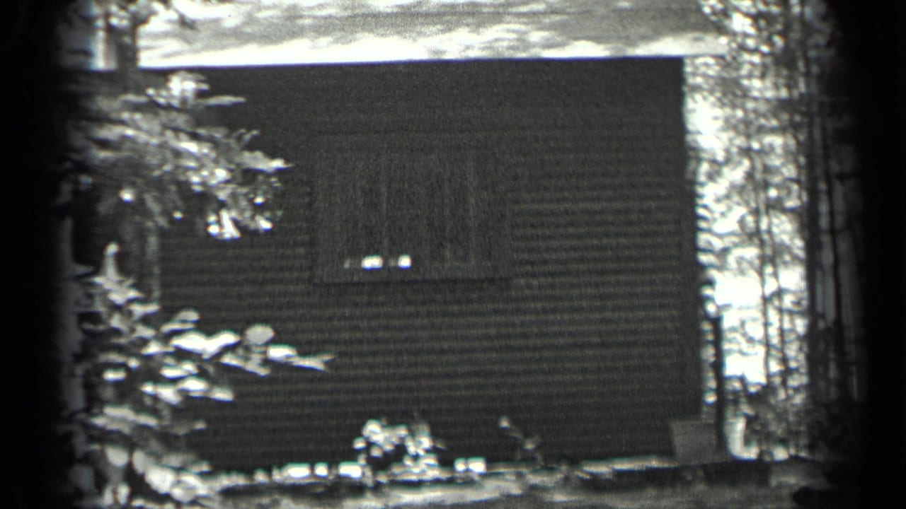1939 Long Lake, Canada home-movie frame showing a wooded cabin exterior with horizontal siding and a small window.